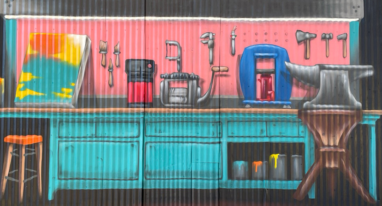 A painted mural of a metalsmithing workbench and tools on the studio wall